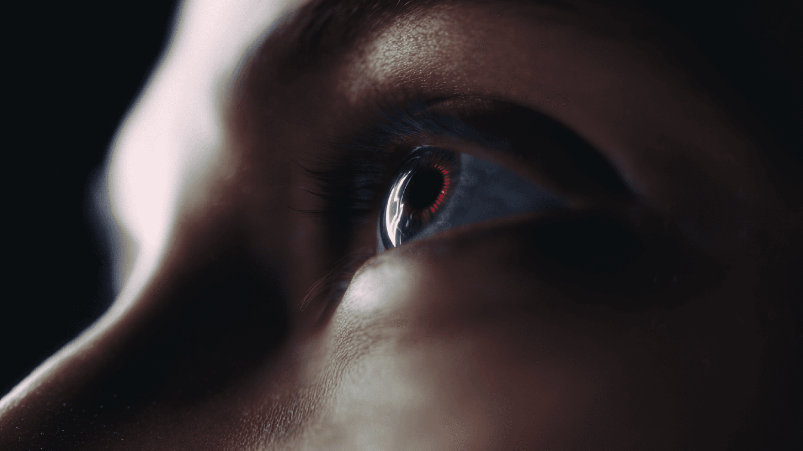 Close-up of a human eye, showcasing intricate details with a blue iris and a faint red reflection in the pupil.