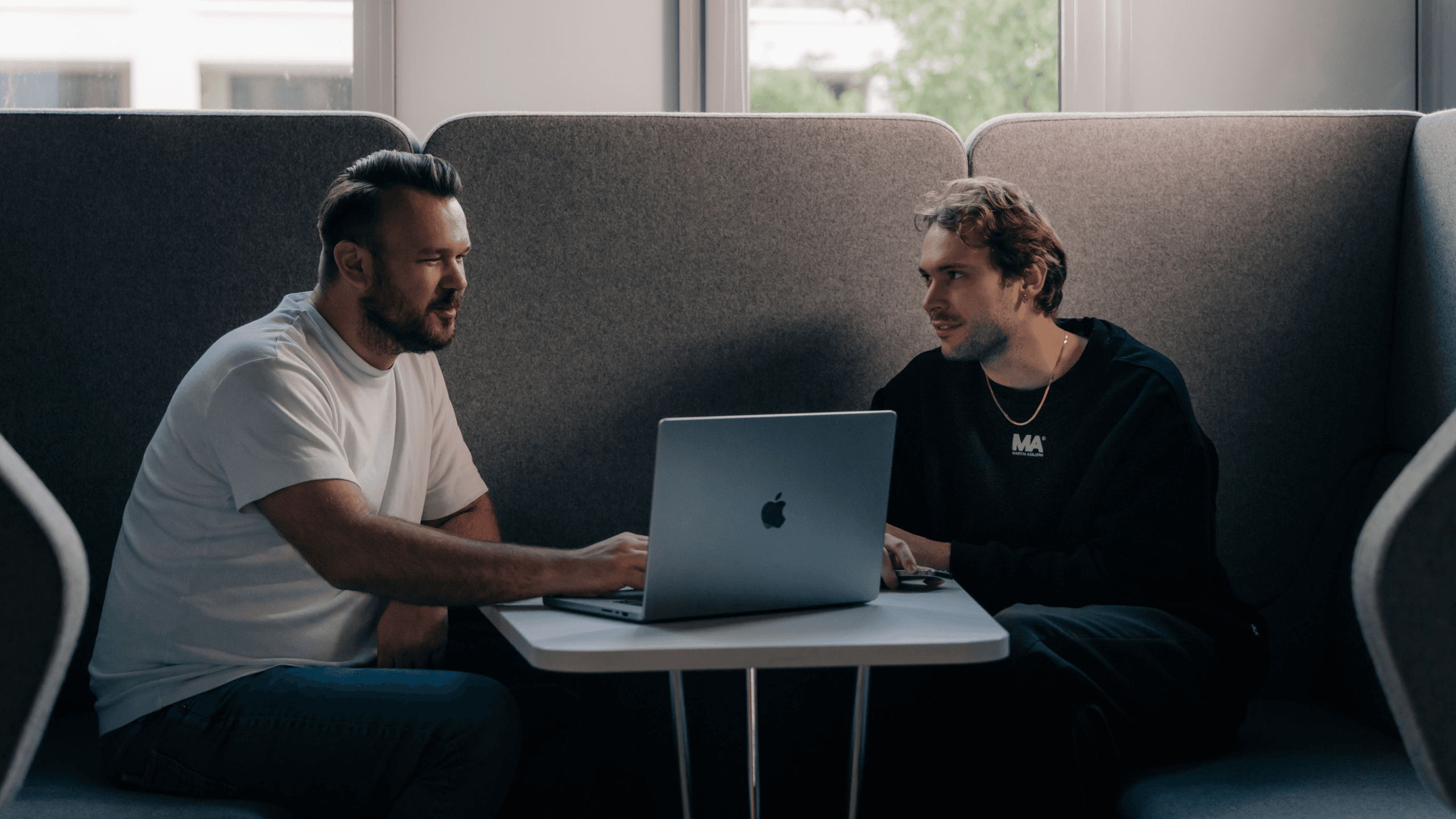 Two men sit at a table in a cozy workspace