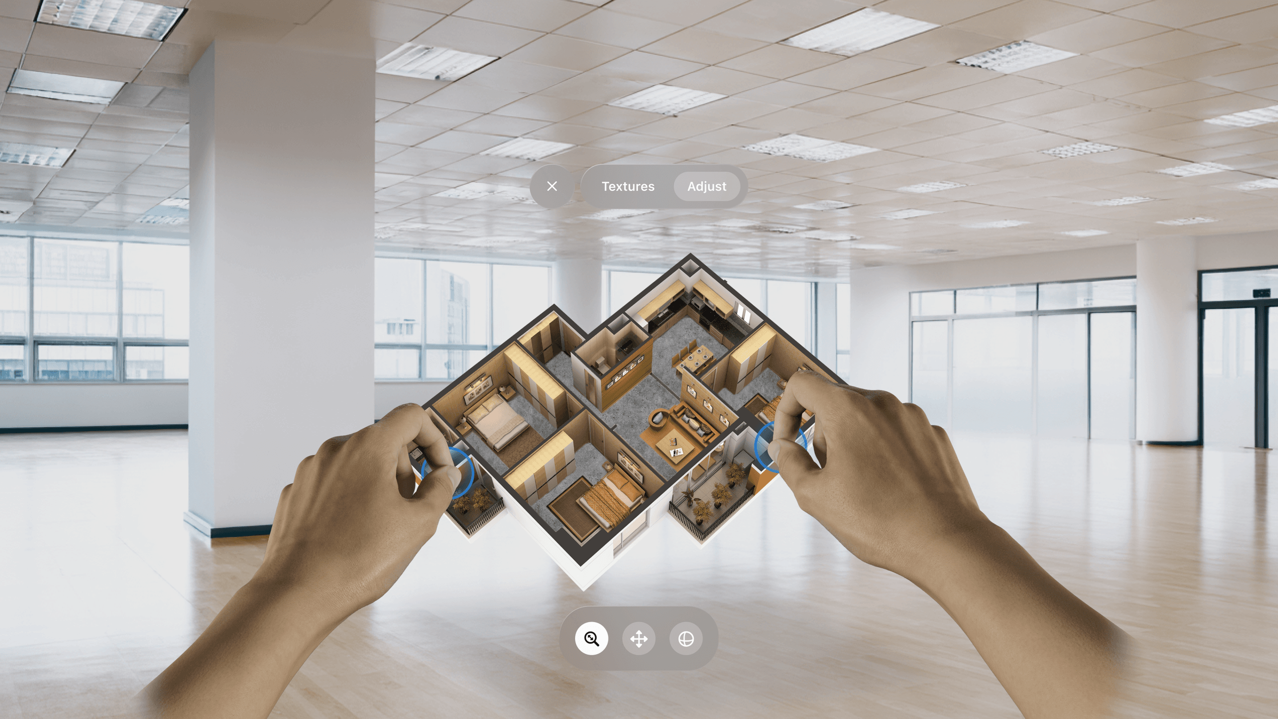 Two hands manipulate a 3D floor plan above an empty room with large windows and a polished floor.